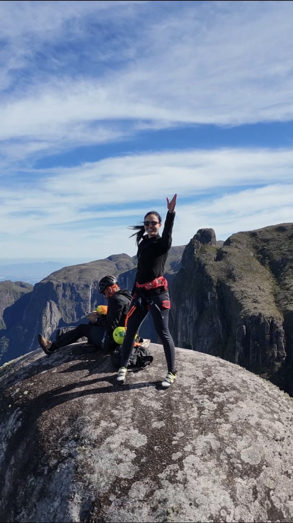 Escaladora celebrando no cume da Agulha do Diabo com o canyon profundo da Serra dos Órgãos ao fundo