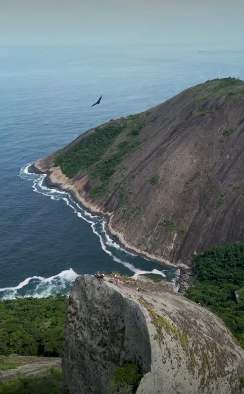 Vista aérea da Agulha Guarischi com urubu voando sobre a formação e a Serra do Tiririca ao fundo