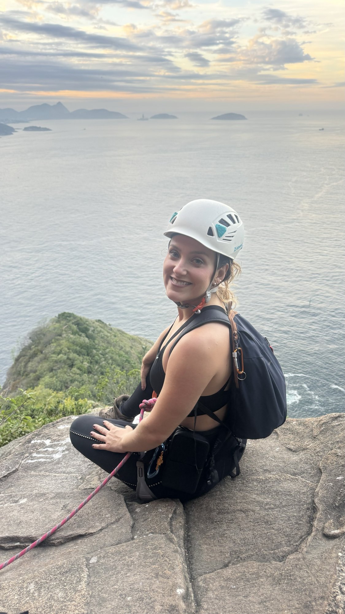 Escalador no topo do Costão do Pão de Açúcar com Urca e o mar aberto ao fundo