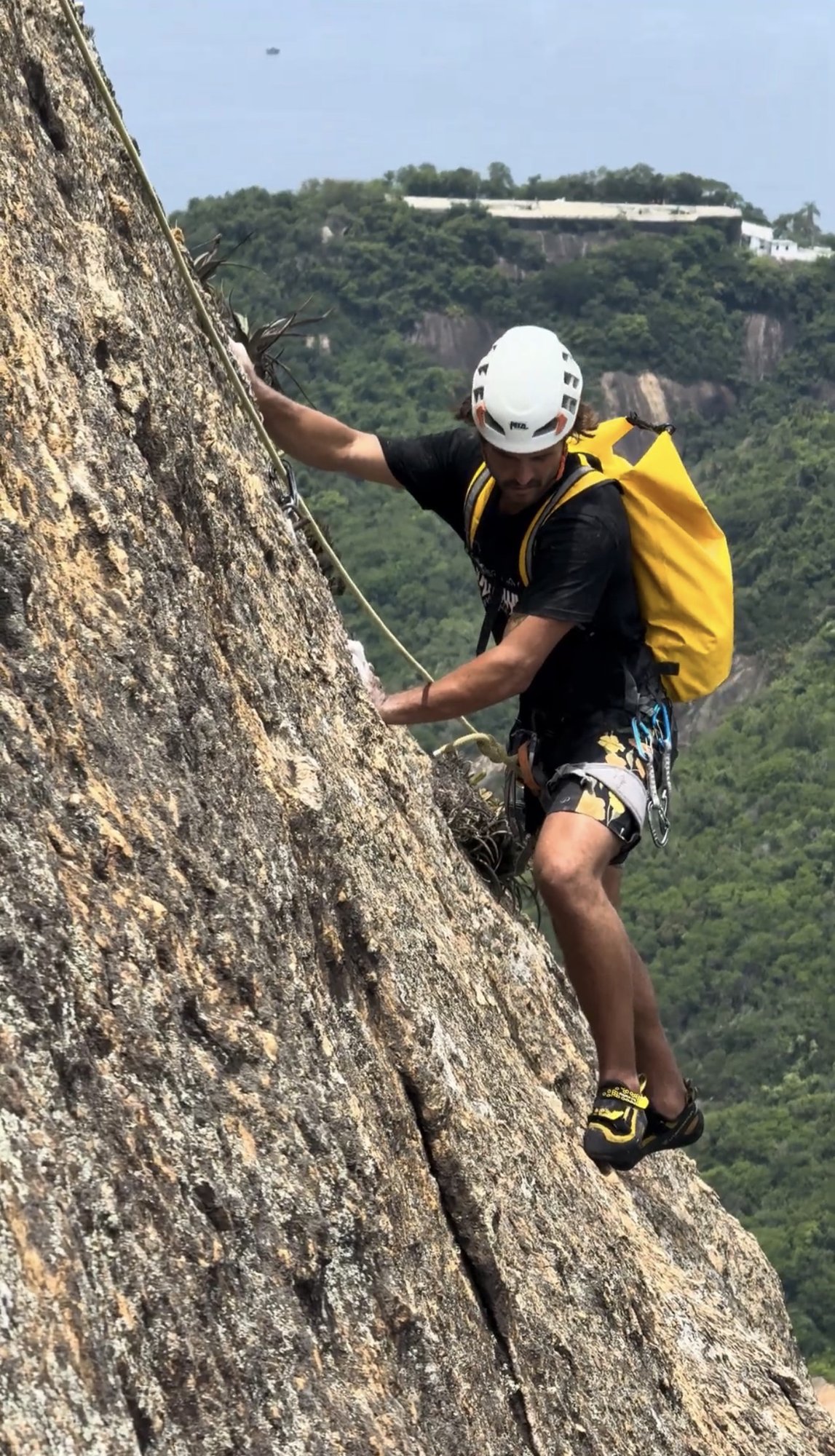 Escalador com capacete amarelo em close-up na face do Pão de Açúcar