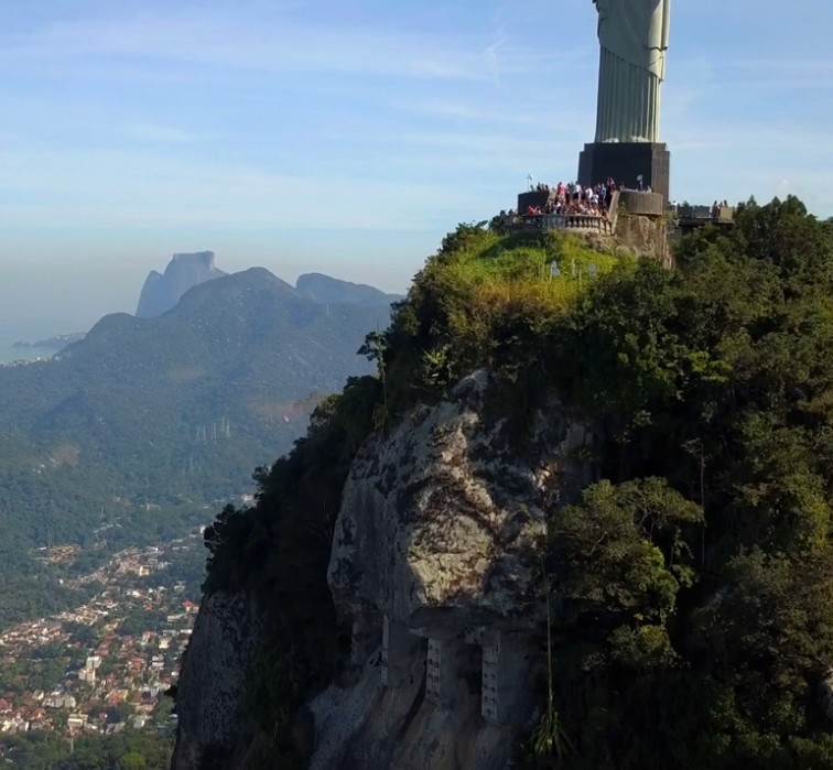 Cristo Redentor visto lateralmente do topo do Corcovado com Rio de Janeiro abaixo
