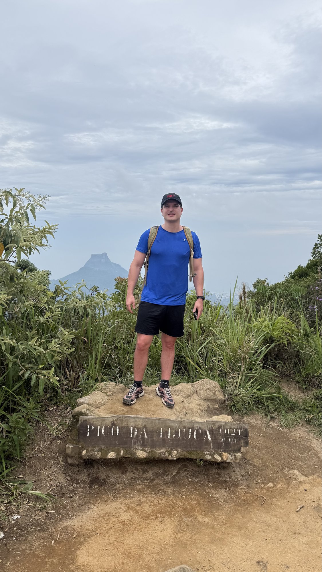 Escalador ao lado da placa de cume do Pico da Tijuca a 1021 metros de altitude