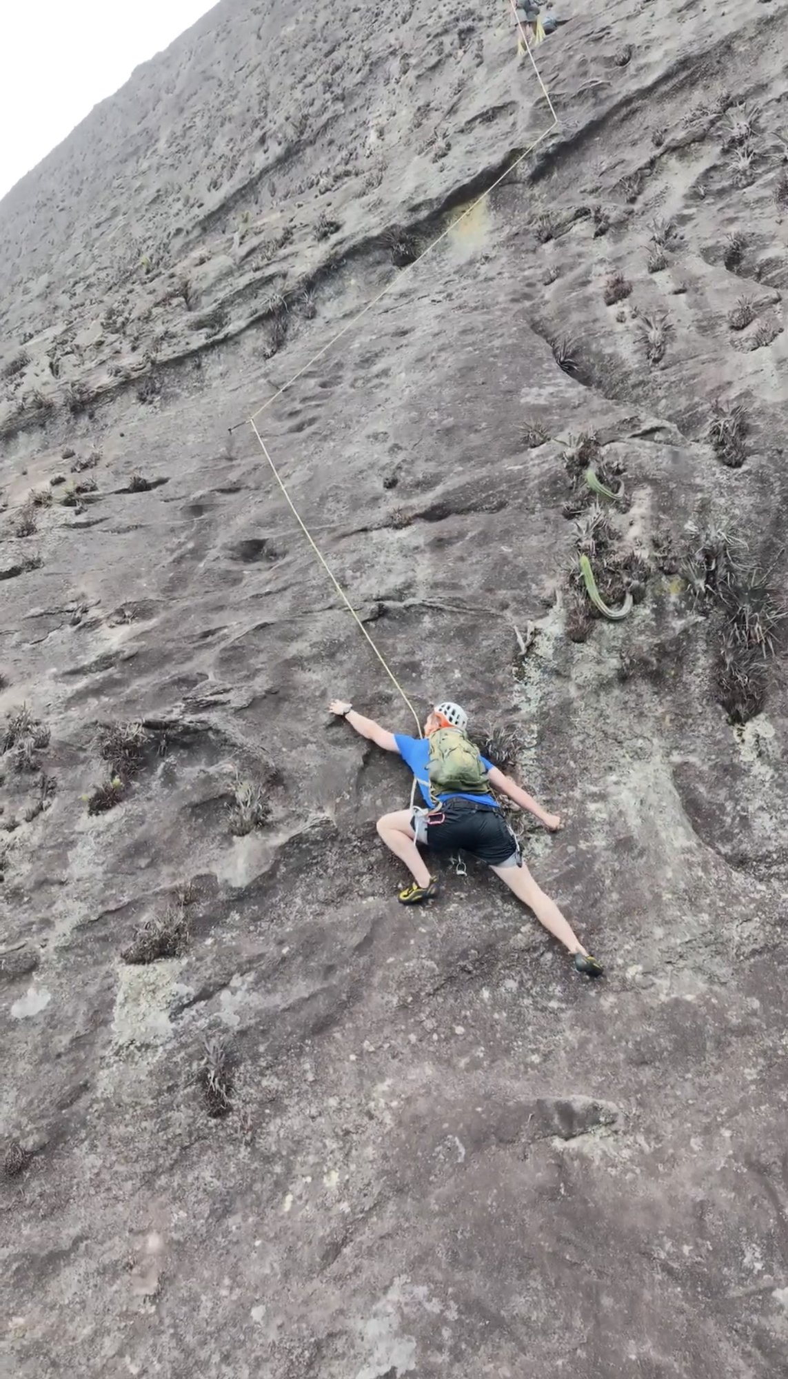 Escaladora de costas em placa inclinada escura na Via Paraíso Perdido no Pico da Tijuca