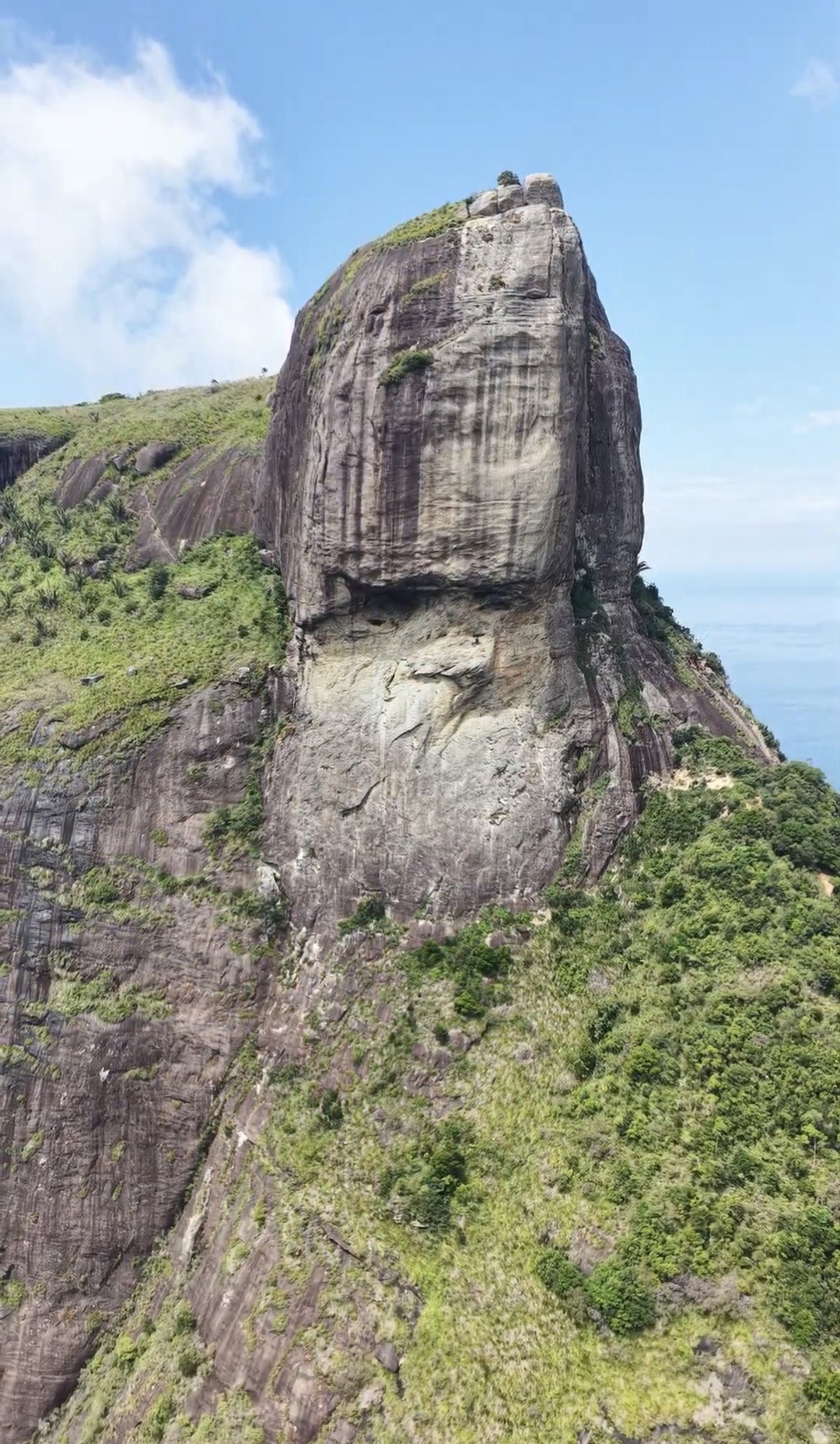 Escaladora em plaquê inclinado na face da Pedra da Gávea com Barra da Tijuca e Lagoa de Marapendi ao fundo