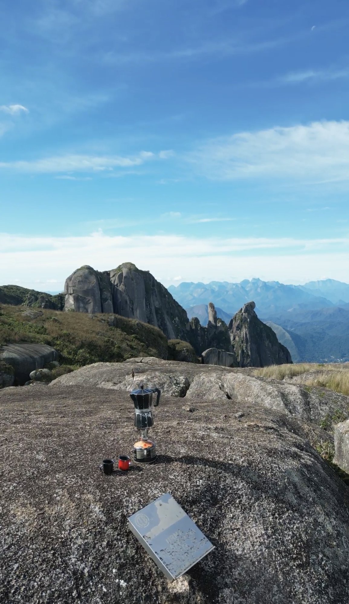 Café preparado em fogareiro sobre placa de granito no bivaque do Garrafão com torres rochosas e Serra dos Órgãos ao fundo