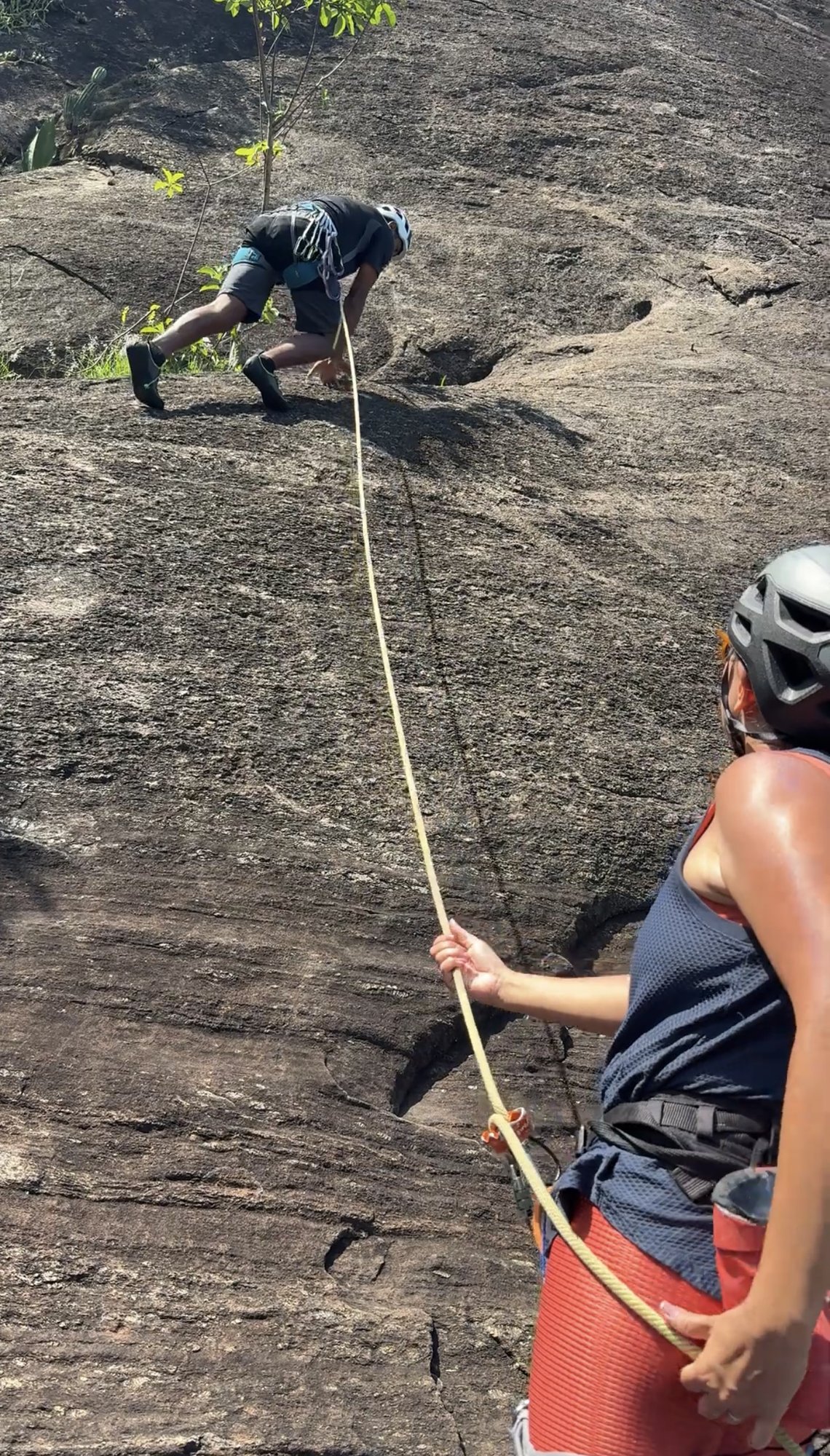 Participante equipado com arnês e capacete durante batismo de escalada no Rio de Janeiro