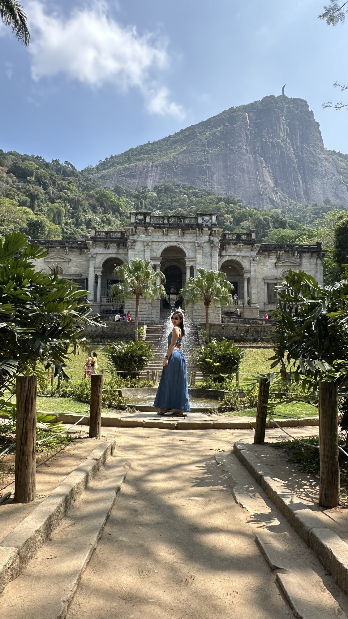 Gruta e cascata natural no interior do Parque Lage com reflexos na água parada