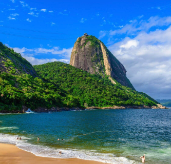 Praia com mar turquesa e Pão de Açúcar ao fundo no Rio de Janeiro