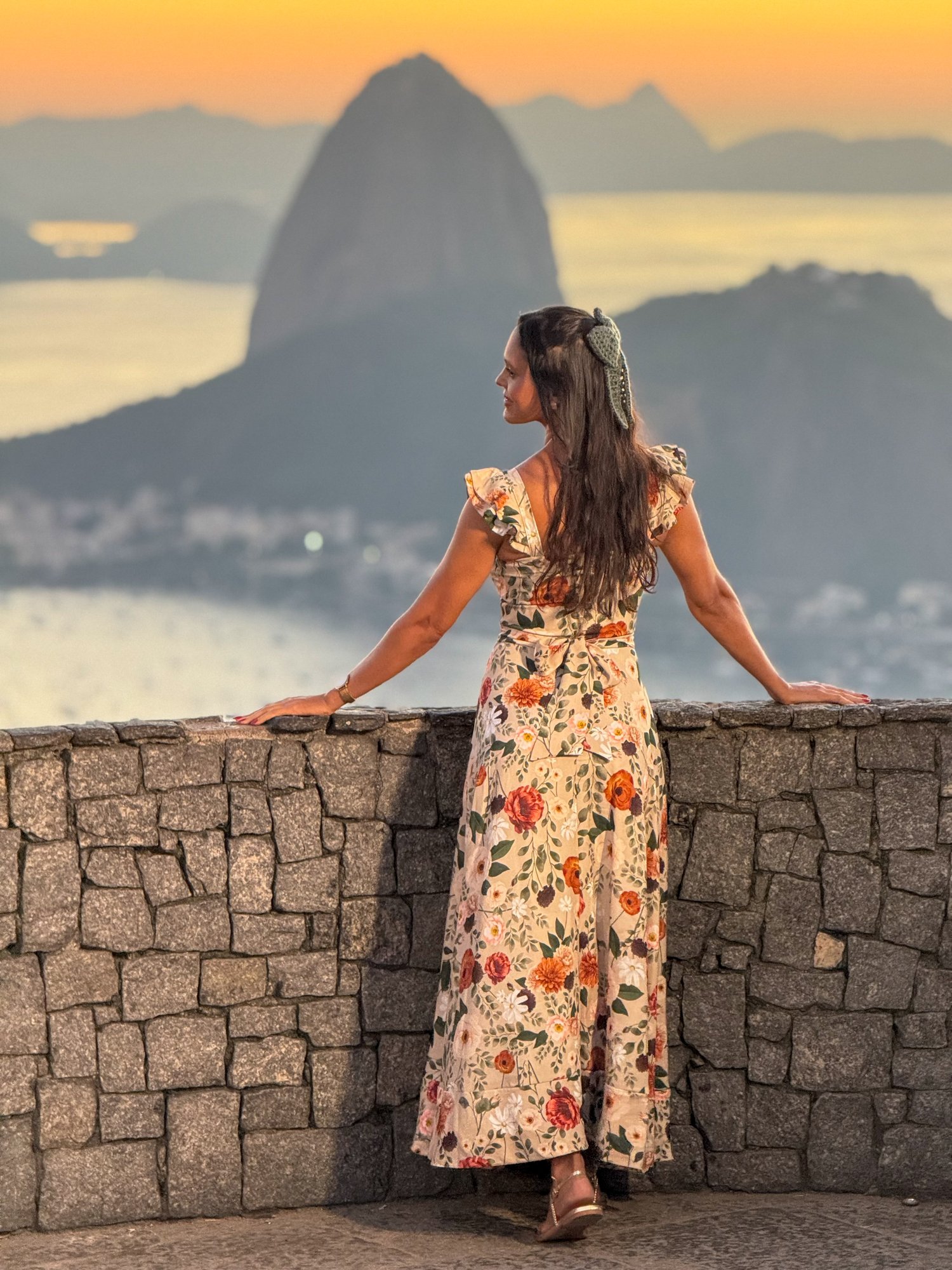 Mulher de vestido floral no Mirante Dona Marta com Pão de Açúcar ao entardecer