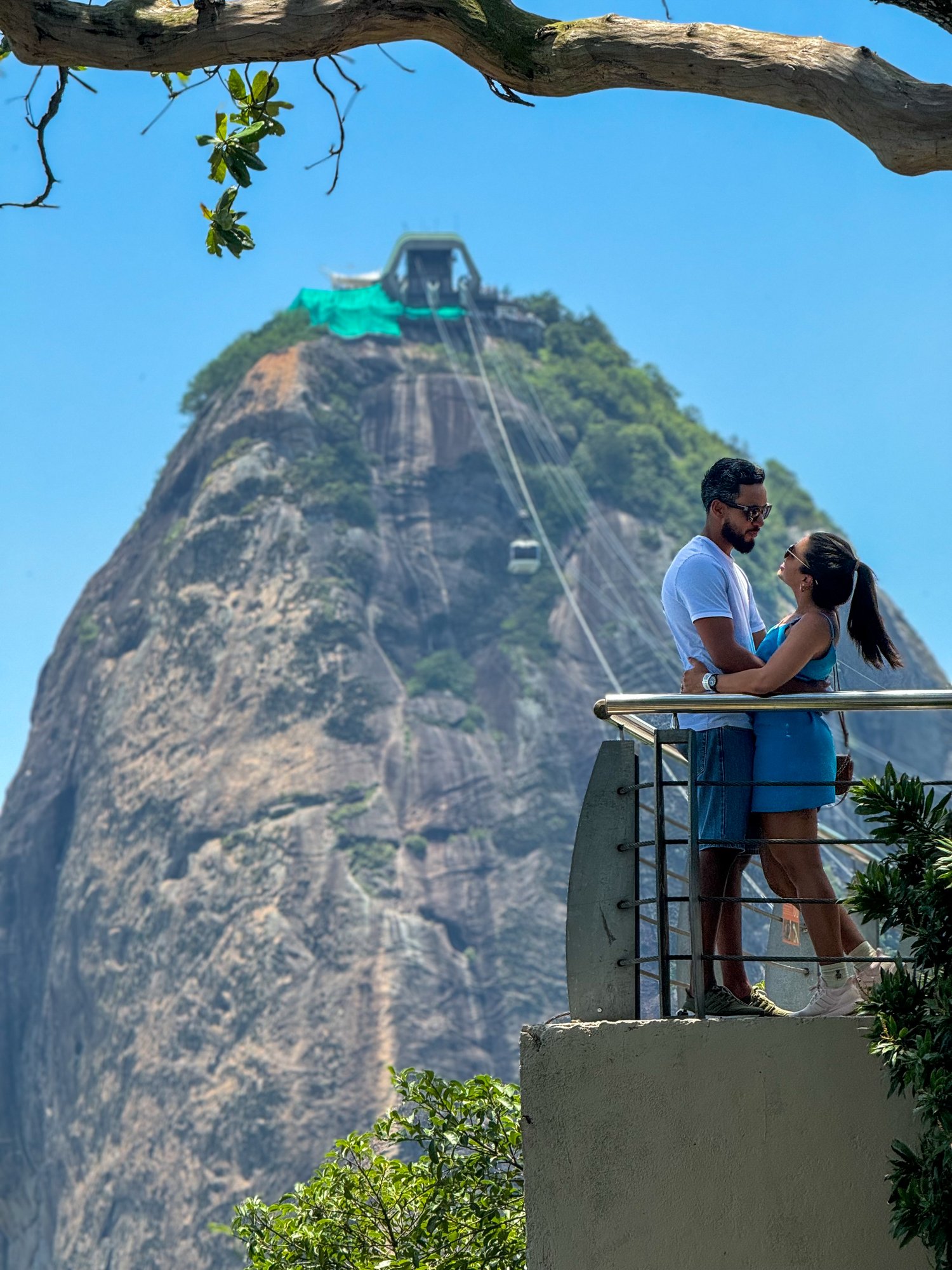 Casal no mirante do Pão de Açúcar com bondinho ao fundo