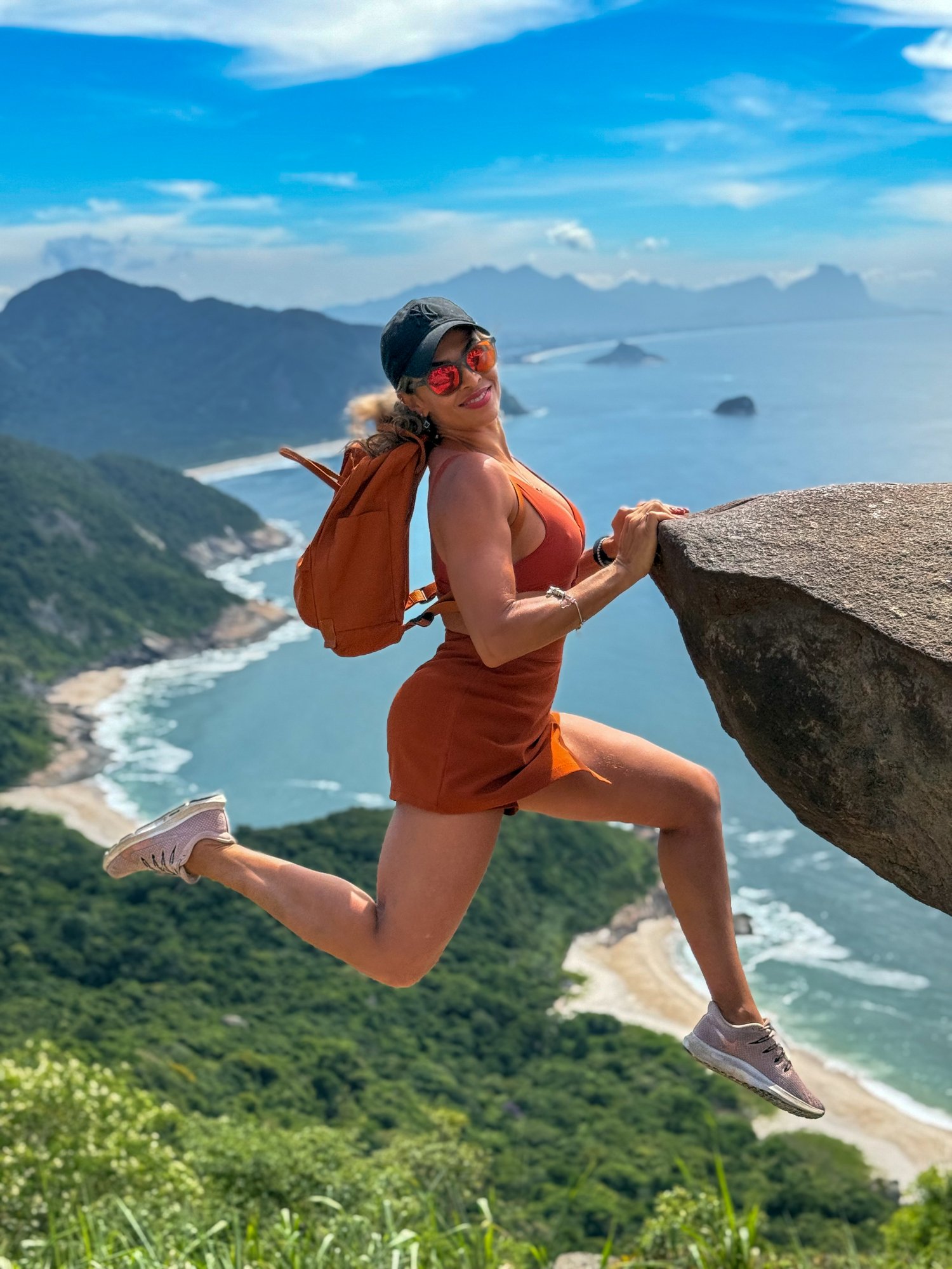 Aventureira segurando na rocha da Pedra do Telégrafo com vista para o mar